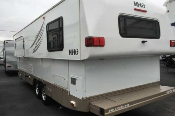 Vitt Hi-Lo fritidsfordon med utfälld lastramp, parkerat utomhus.